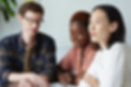 Three creatives in discussion sitting around a table.